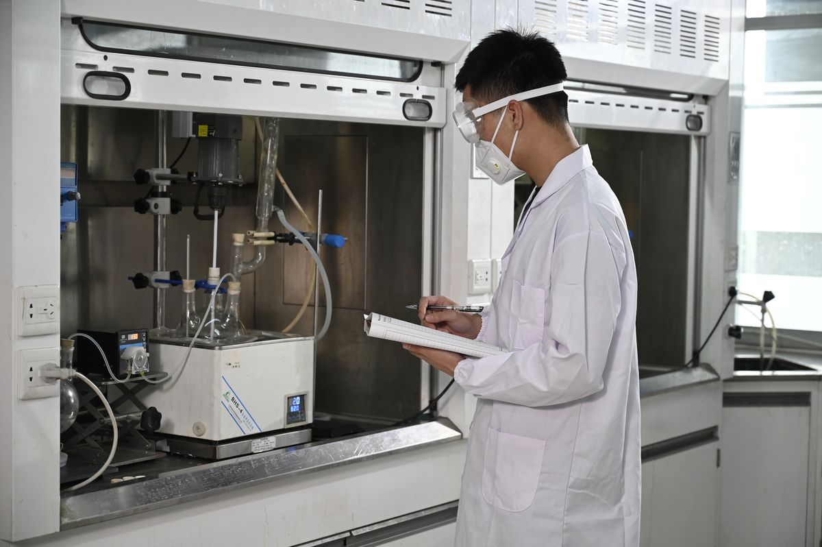 Researcher recording data at a fume hood